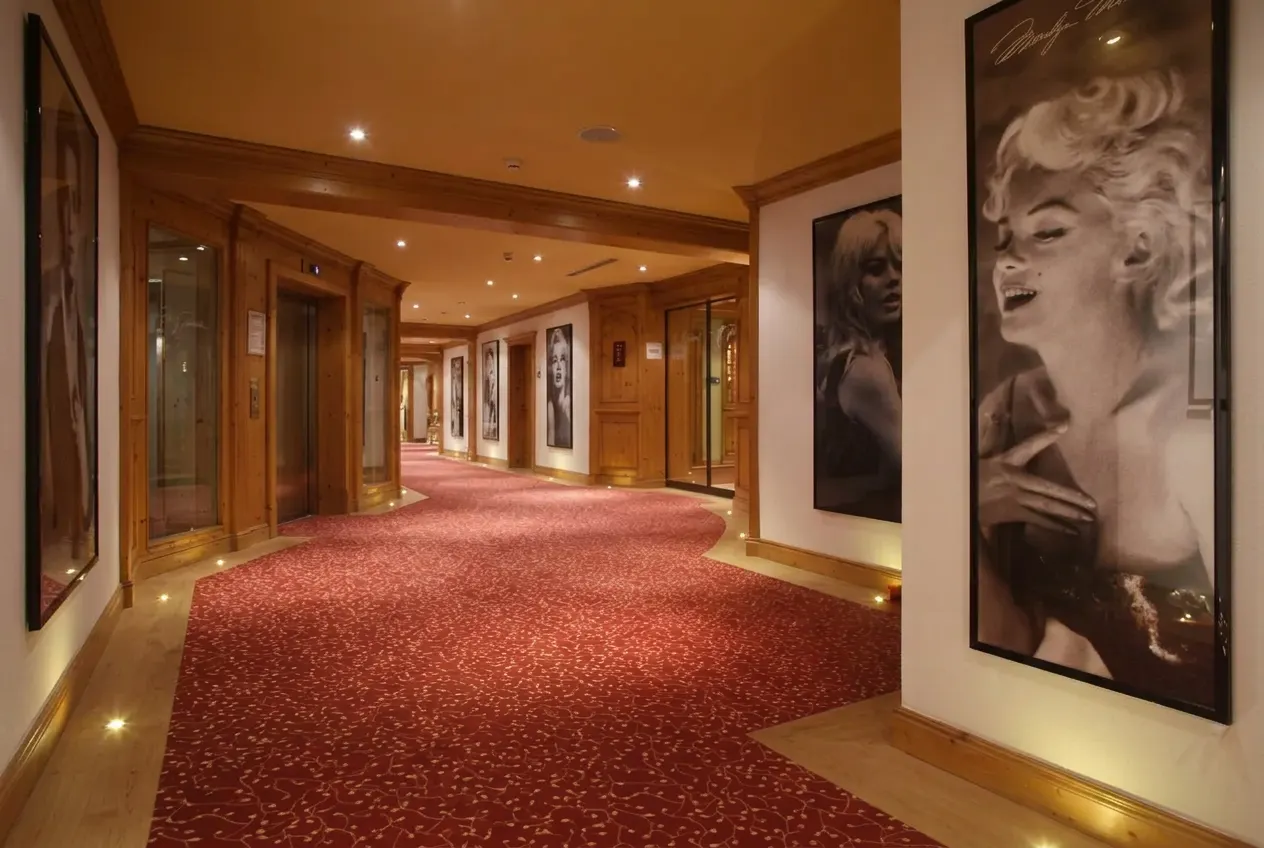 Couloir d'hôtel avec spots au sol, portraits encadrés et visage de Marilyn Monroe visible