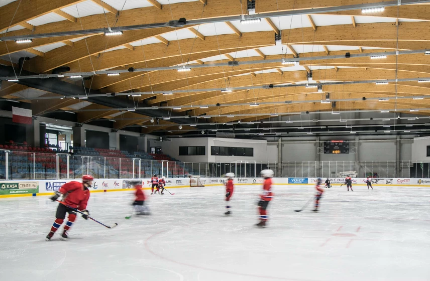 Patinoire couverte éclairée par des lignes lumineuses LED suspendues sous charpente bois