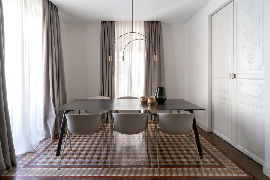 Salle à manger éclairée par une suspension arquée à trois bras