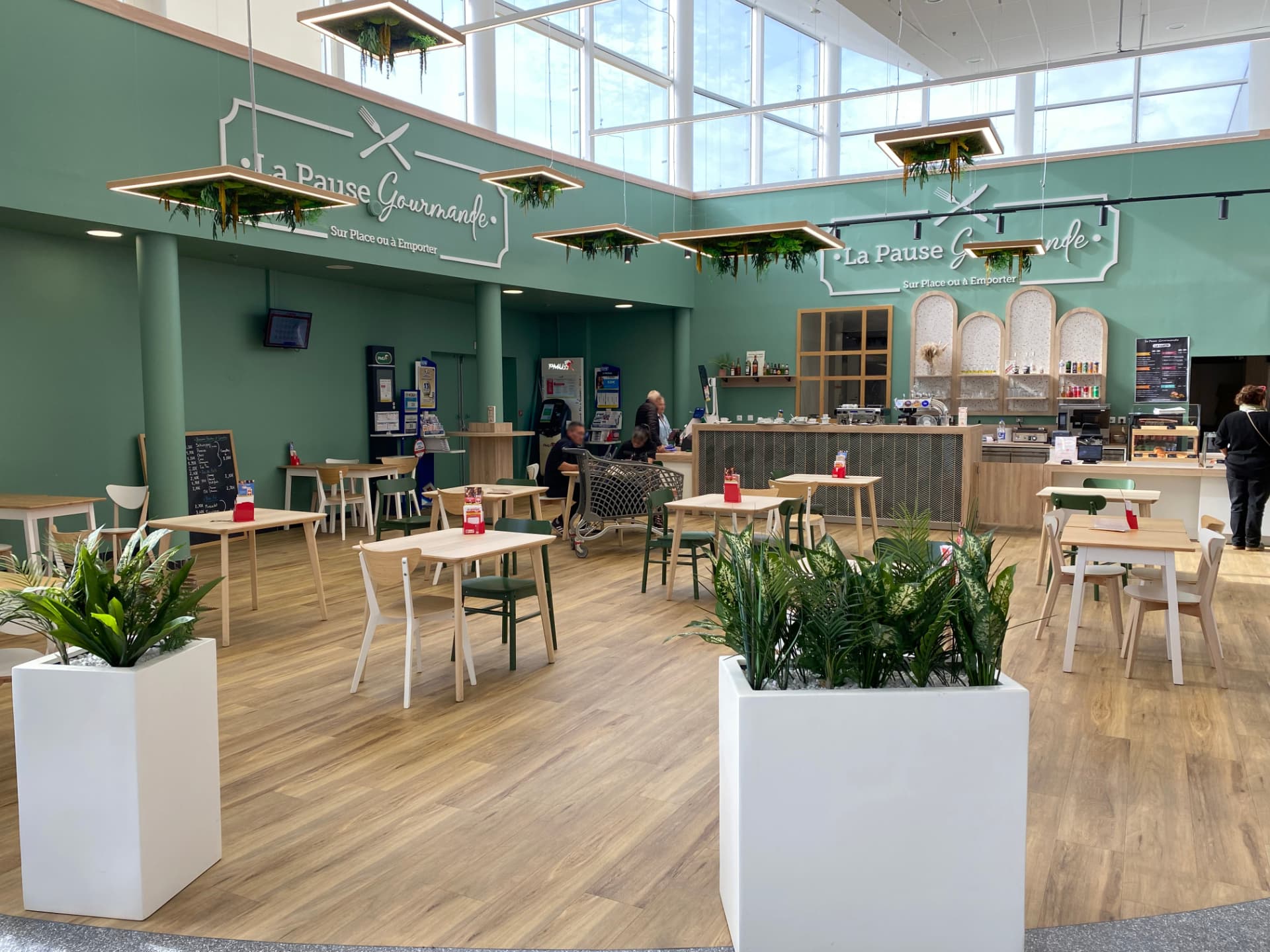 Espace de restauration en centre commercial avec panneaux LED végétalisés suspendus