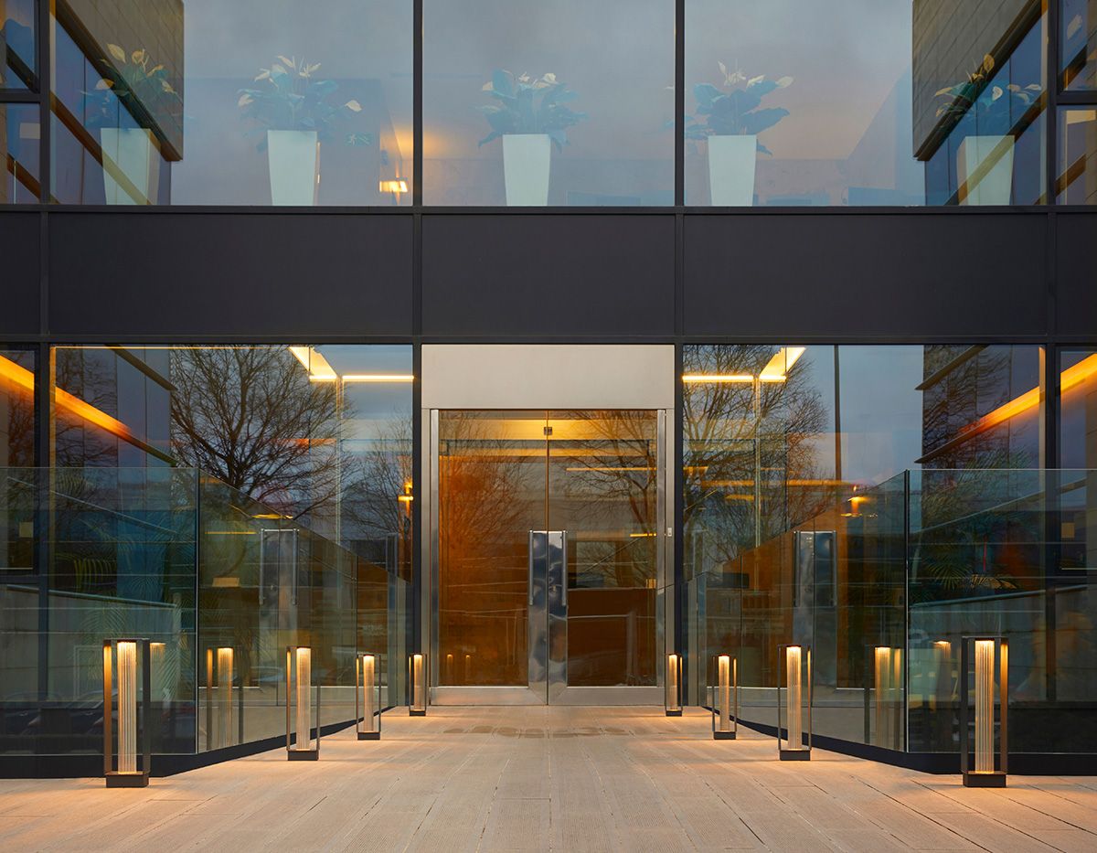 Entrée vitrée de bâtiment tertiaire éclairée par bornes et lignes LED