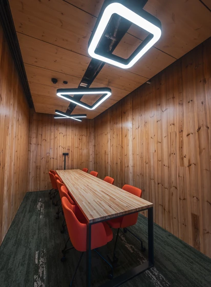 Salle de réunion en bois éclairée par suspensions LED géométriques