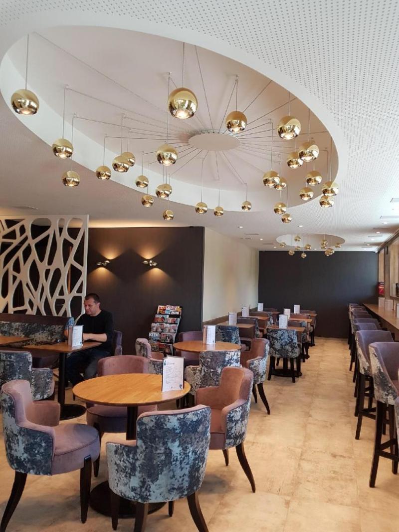 Salle de restaurant ou lounge hôtelier éclairée par des suspensions globes dorées